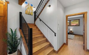 A wooden staircase with black railings leading to a room with a bed and a window. - The Brush Creek Lookout - Home Away From Home (Crested Butte)