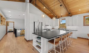 A spacious kitchen with a large island, white cabinetry, and a wooden ceiling. - The Brush Creek Lookout - Home Away From Home (Crested Butte)