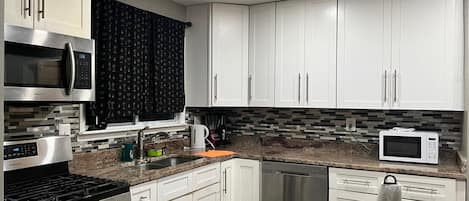 A modern kitchen with white cabinets, stainless steel appliances, and a tiled backsplash.
