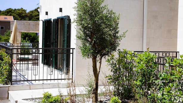 A building with a gated entrance, a tree in the foreground, and a clear sky. - Apartments Sava (Tivat)