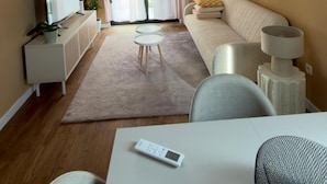 A modern living room with a flat-screen TV, a sofa, a coffee table, and a dining area with a table and chairs. - Apartments Sava (Tivat)