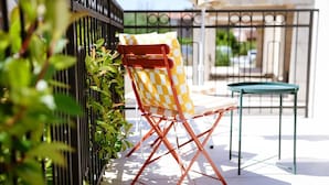 A patio area with a folding chair and a small table, surrounded by greenery and a metal fence. - Apartments Sava (Tivat)