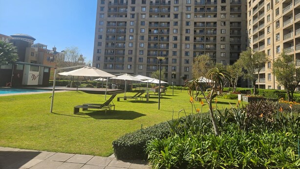 Un patio con piscina, sillones de descanso y sombrillas.