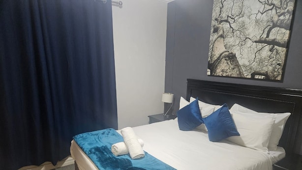 Et hotelværelse med en seng, et natbord, en lampe og et billede på væggen.