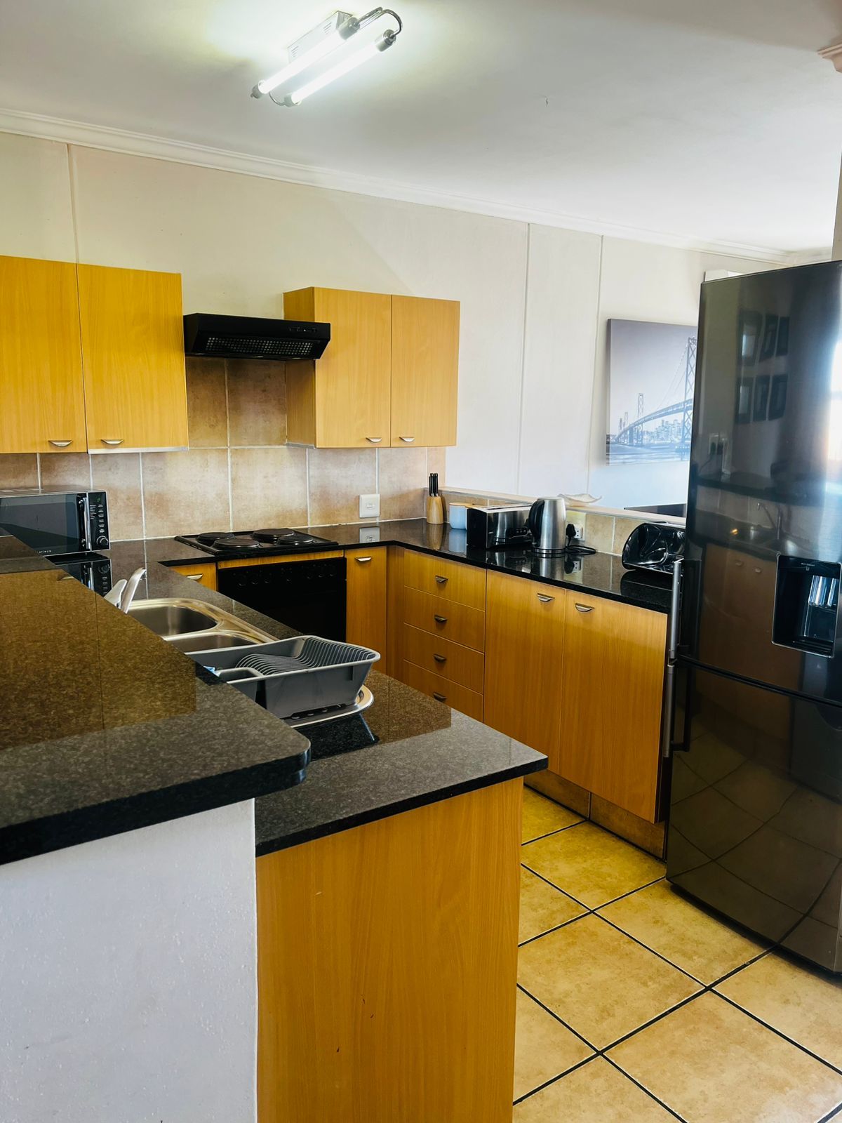 Una cucina moderna con mobili in legno, un frigorifero in acciaio inossidabile e un forno a microonde.