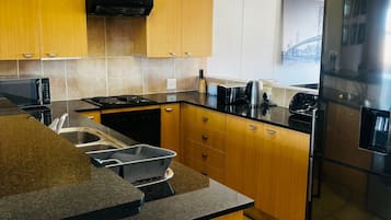 Una cucina moderna con mobili in legno, un frigorifero in acciaio inossidabile e un forno a microonde.