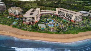 Un resort con varias edificaciones, un área de piscina central y acceso a la playa.