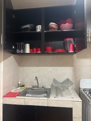 Ett kök med en inbyggd diskmaskin, en diskho med blandare och en spis.