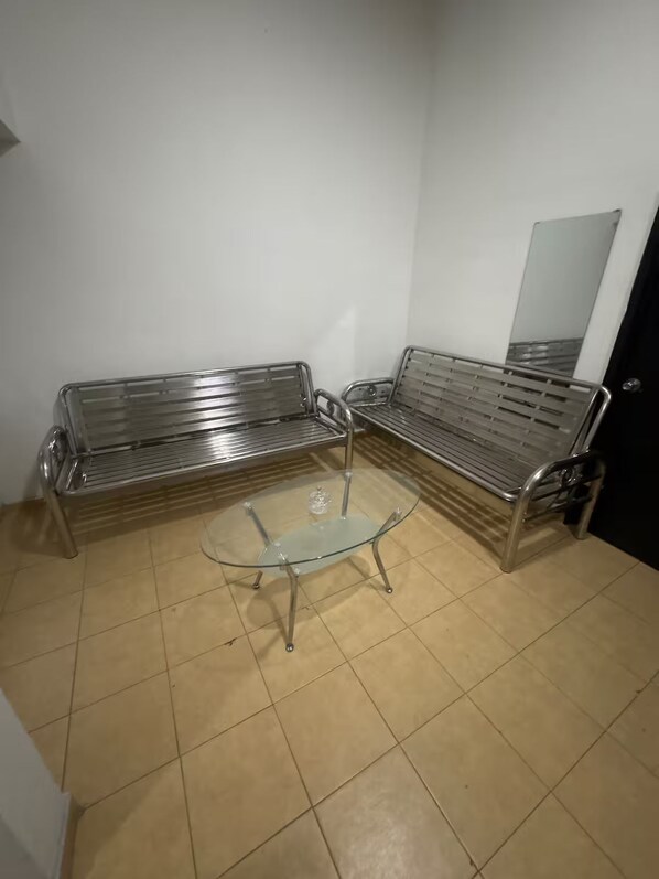 Una habitación con dos sofás de estructura metálica y una mesa de centro de vidrio.