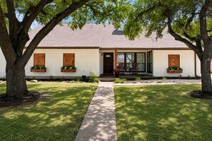 A two-story house with a front porch, a brick exterior, and a well-maintained lawn. - The Howdy Home | Near Texas A&M | Golf Course Views | Sleeps 10 (Bryan)