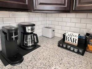 A kitchen with a coffee maker, toaster, and a coffee bar sign. - The Howdy Home | Near Texas A&M | Golf Course Views | Sleeps 10 (Bryan)