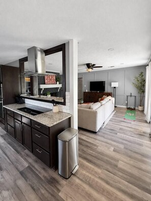 A modern kitchen with a built-in stove, a large island, and dark cabinetry. - The Howdy Home | Near Texas A&M | Golf Course Views | Sleeps 10 (Bryan)