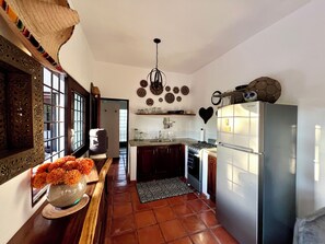 A compact kitchen with a refrigerator, stove, and sink. There is a decorative heart on the wall and a vase with flowers on the counter. - Private garden retreat 1-bedroom casita with AC in charming Sayulita (Sayulita)