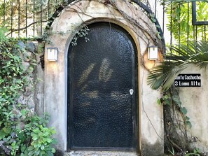 A black door with a textured surface, surrounded by greenery and a stone wall. - Private garden retreat 1-bedroom casita with AC in charming Sayulita (Sayulita)