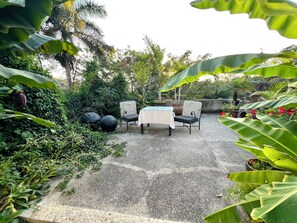 A garden patio with a table and chairs, surrounded by lush greenery and plants. - Private garden retreat 1-bedroom casita with AC in charming Sayulita (Sayulita)