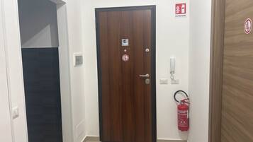 Un pasillo con una puerta de madera, un extintor y un letrero de Wi-Fi.