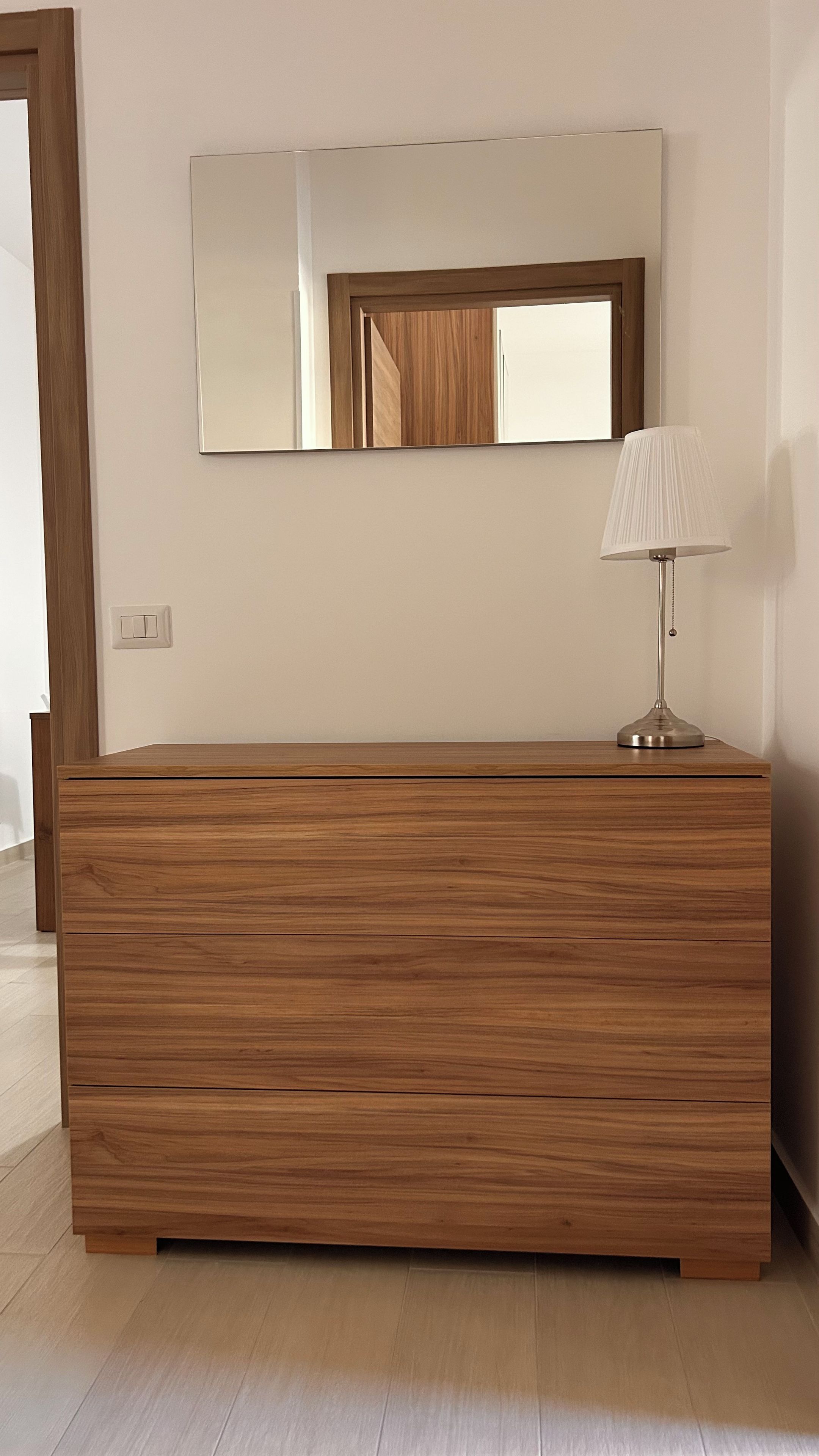 Un aparador de madera con un espejo arriba y una lámpara encima.