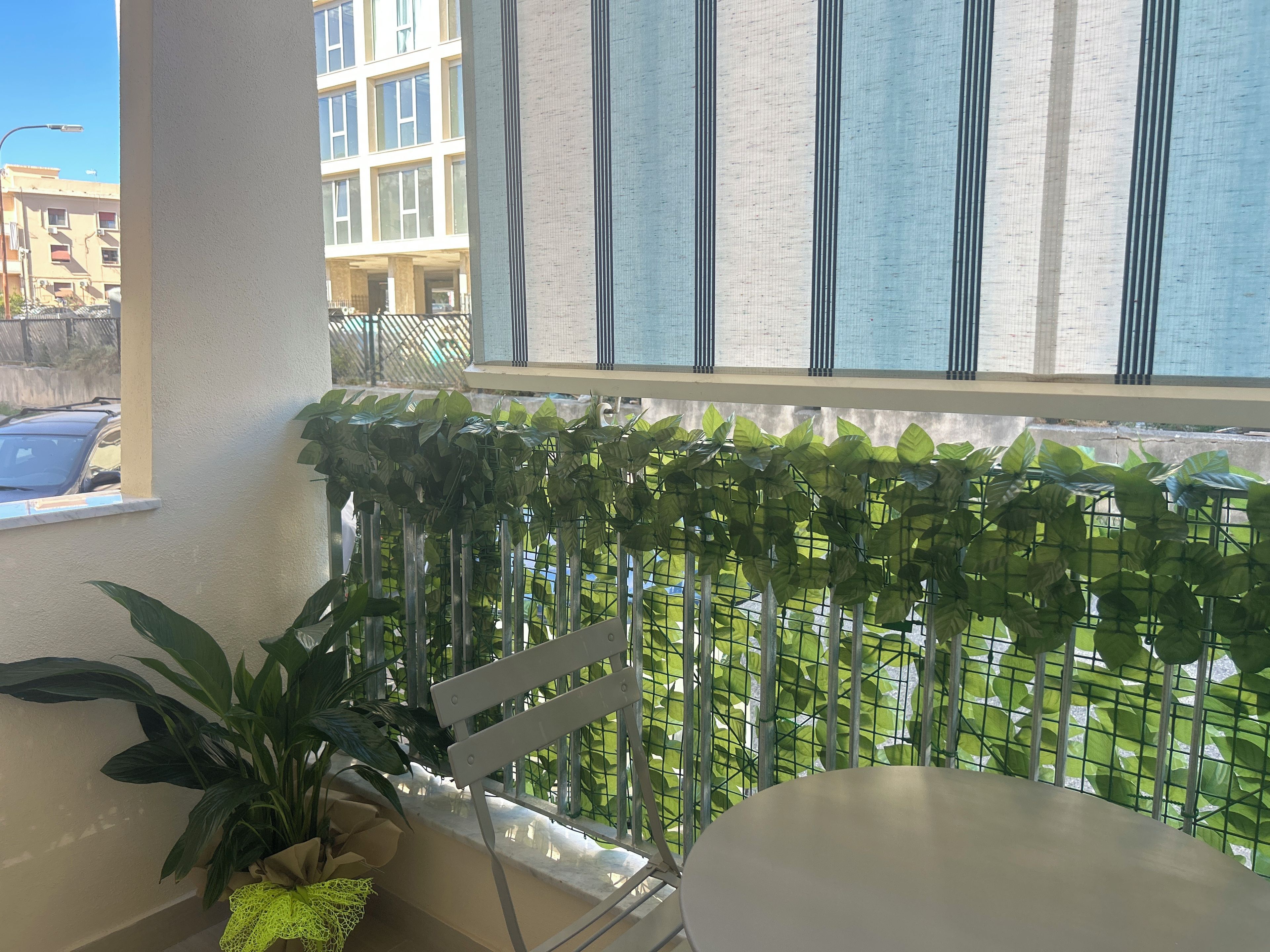 Ein Balkon mit Metallgeländer, einem Blumentopf und einem Stuhl.