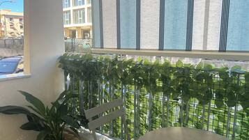 Ein Balkon mit Metallgeländer, einem Blumentopf und einem Stuhl.