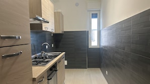 Una cucina moderna con mobili in legno, una cappa aspirante in acciaio inossidabile, un forno integrato e un rivestimento a parete in piastrelle nere.