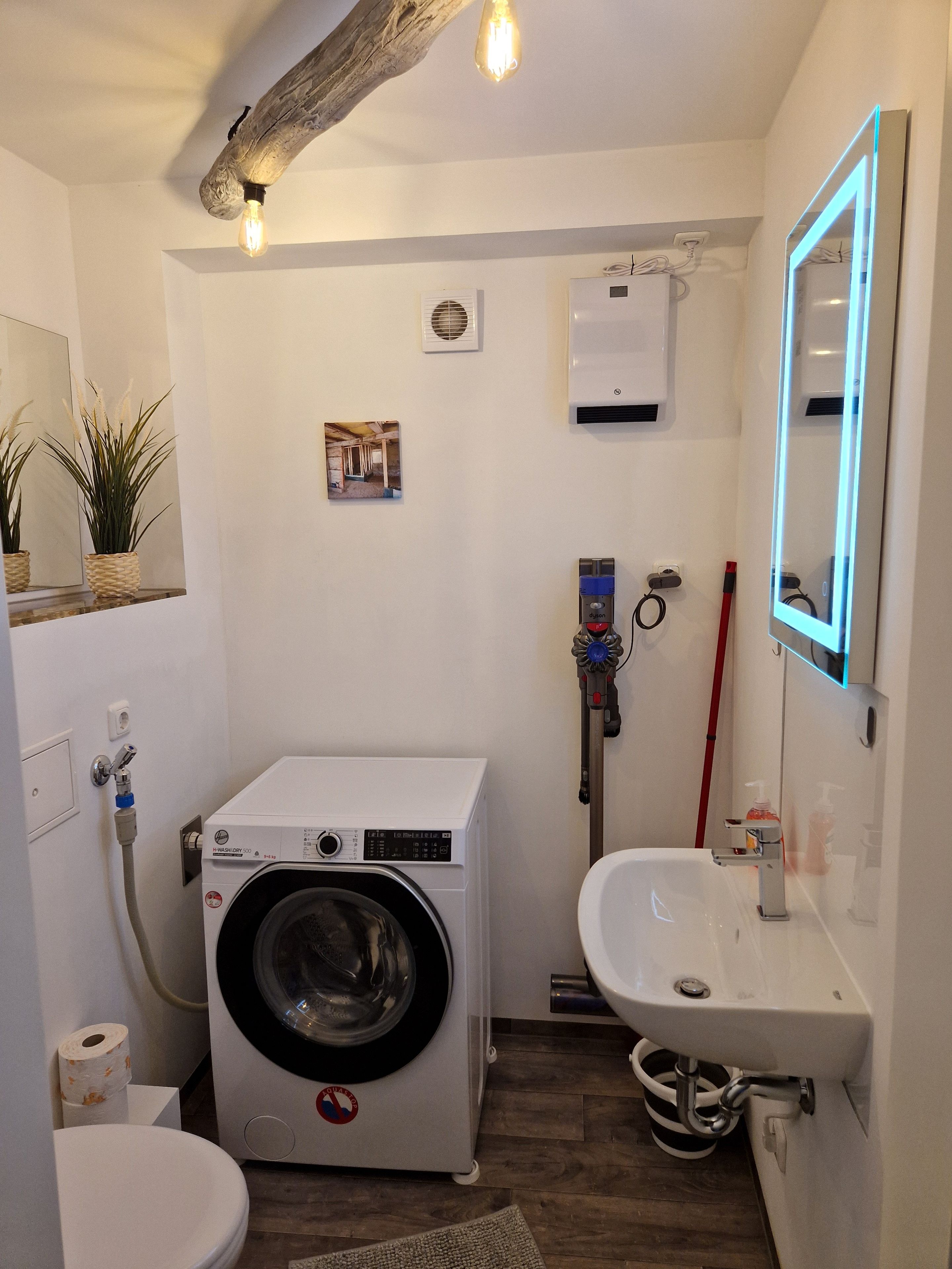 Un baño pequeño con lavadora, lavamanos y espejo.