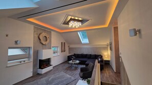 A modern living room with a fireplace, a sofa, a coffee table, and a skylight.