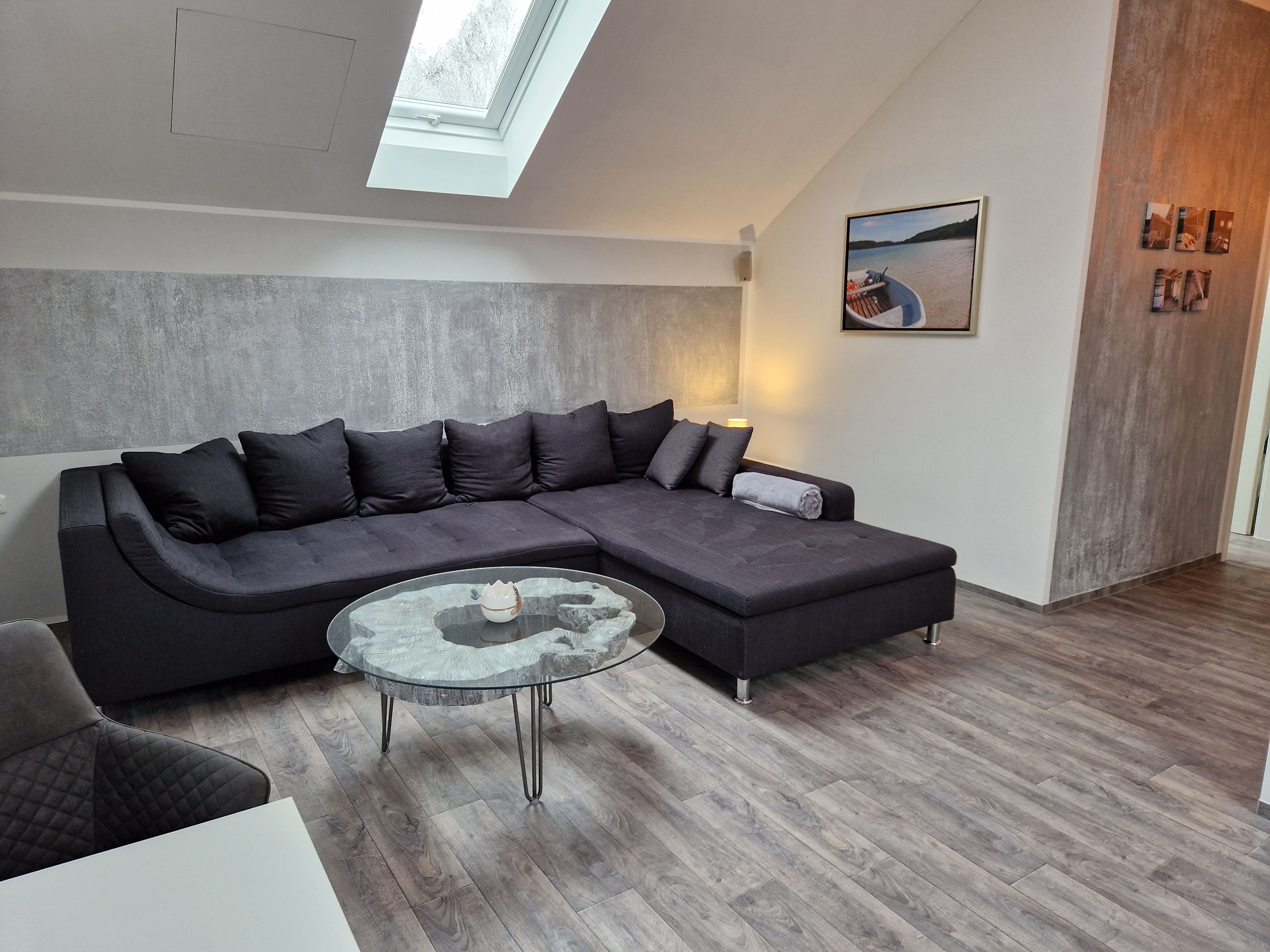 Ein modernes Wohnzimmer mit einer Eckcouch, einem Glastisch und einem Oberlicht.