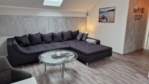 A modern living room with a sectional sofa, a glass coffee table, and a skylight. - Holiday Home 'Ferienhaus in Fürstensee Wald See' with Shared Pool, Private Terrace and Wi-Fi (Neustrelitz)