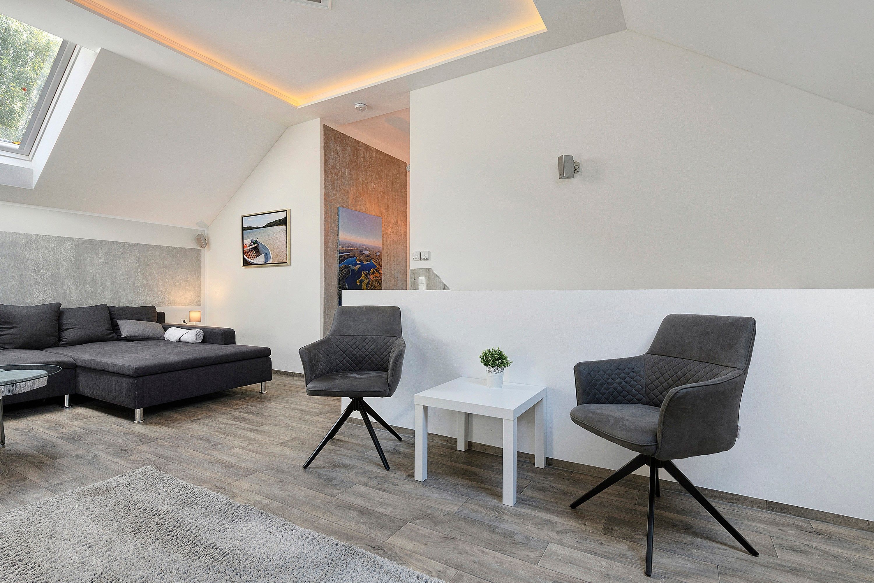 Ein modernes Wohnzimmer mit einer Couch, zwei Sesseln, einem kleinen Tisch und einem Gemälde an der Wand.