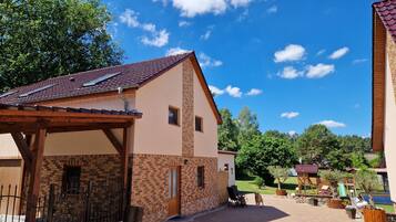 Ein zweistöckiges Gebäude mit einer überdachten Terrasse, einer Ziegel-Fassade und blauem Himmel.