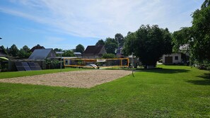 Un patio trasero con una red de voleibol, un cobertizo pequeño y paneles solares.