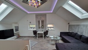 A modern loft apartment with a high ceiling, skylights, a flat-screen TV, a sofa, a dining table, and a small kitchen area. - Holiday Home 'Ferienhaus in Fürstensee Wald See' with Shared Pool, Private Terrace and Wi-Fi (Neustrelitz)