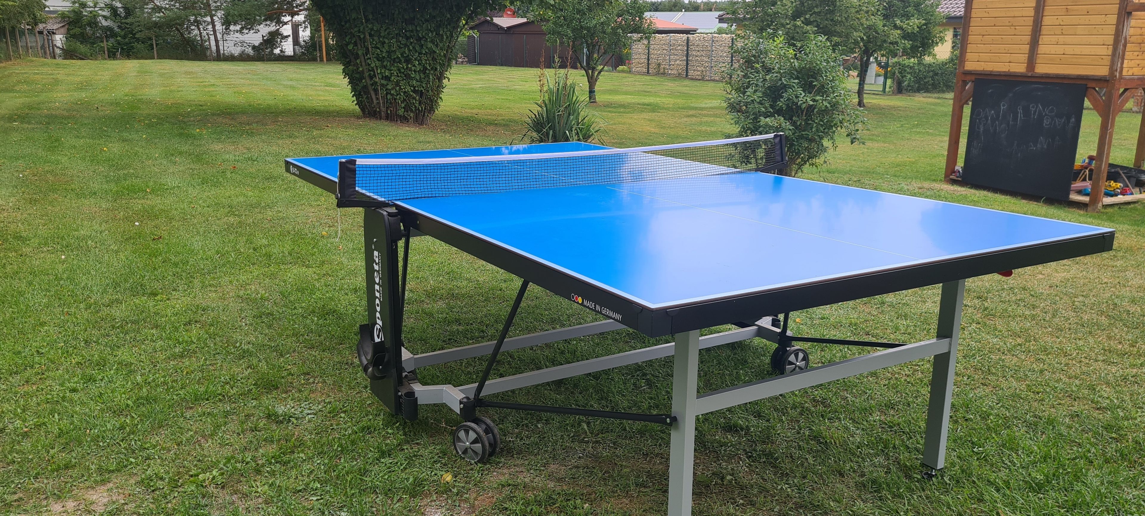 Ein tragbarer Tischtennis-Tisch auf einer grünen Rasenfläche.