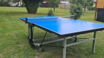 Ein tragbarer Tischtennis-Tisch auf einer grünen Rasenfläche.