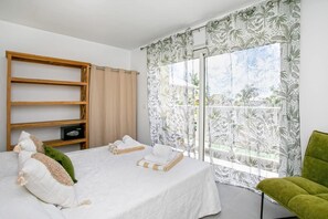 Ein Schlafzimmer mit einem Bett, einem hölzernen Regal, einem grünen Stuhl und einem Fenster mit Vorhängen.