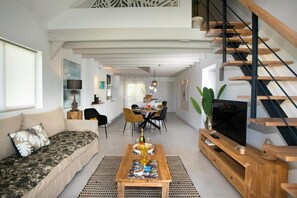 Ein modernes Wohnzimmer mit Sofa, Couchtisch und Fernseher auf einem Holzboden.