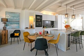 A modern kitchen with a central island, built-in appliances, and pendant lighting. - Maison Sylvie  Résidence Maracuja Orient Bay (Orient bay)
