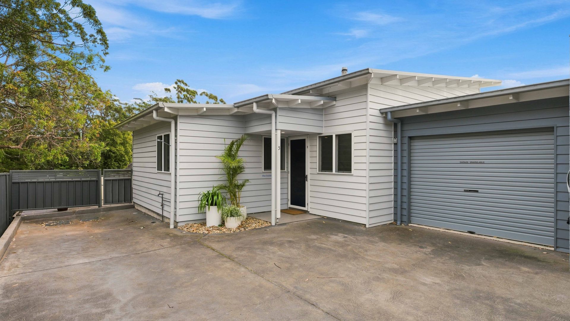 A residential building with a garage, a covered entryway, and a concrete driveway.