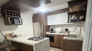 Een moderne keuken met een centraal eiland, inbouwapparatuur en een houten vloer.