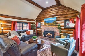 A log cabin interior with a fireplace, leather sofas, and a large window. - Renovated Log Cabin | Mins to Heavenly & Beach (South Lake Tahoe)