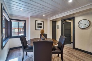 A dining area with a round table, four chairs, a clock on the wall, and a door in the background. - Renovated Log Cabin | Mins to Heavenly & Beach (South Lake Tahoe)