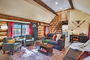 A log cabin interior with a staircase, a sofa, a coffee table, and a dining area. - Renovated Log Cabin | Mins to Heavenly & Beach (South Lake Tahoe)