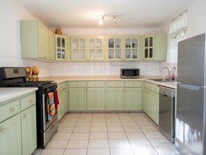 A kitchen with light green cabinets, a microwave, a refrigerator, an oven, and a dishwasher.