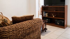A living room with a television on a wooden stand, a sofa, and a bookshelf.