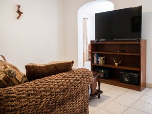 A living room with a television on a wooden stand, a sofa, and a bookshelf.
