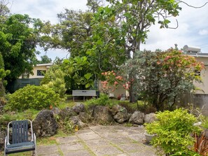 A garden with a patio, rocks, and a bench.