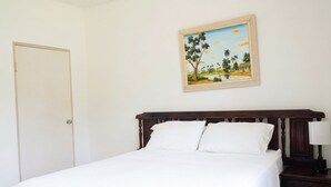 A bedroom with a bed, a nightstand, a lamp, and a painting on the wall.