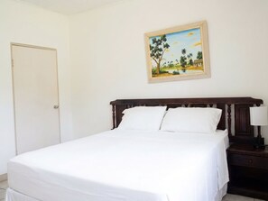 Une chambre à coucher avec un lit, une table de chevet, une lampe et un tableau au mur.
