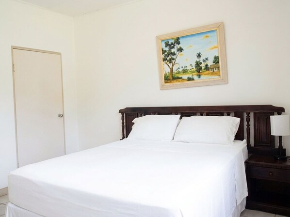 A bedroom with a bed, a nightstand, a lamp, and a painting on the wall.