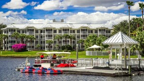 Un hotel frente al agua con muelle, botes a pedal y un pabellón.